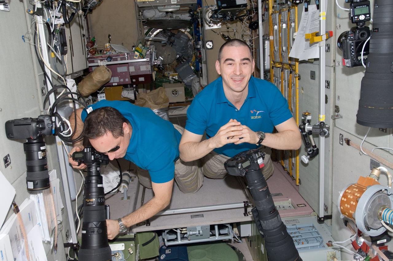 ISS030-E-010663 (11 Dec. 2011) --- Russian cosmonauts Anton Shkaplerov (left) and Anatoly Ivanishin, both Expedition 30 flight engineers, use still cameras to record orbit-to-Earth imagery from windows in the Zvezda Service Module of the International Space Station.