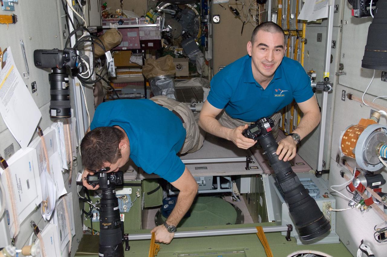 ISS030-E-010665 (11 Dec. 2011) --- Russian cosmonauts Anton Shkaplerov (left) and Anatoly Ivanishin, both Expedition 30 flight engineers, use still cameras to record orbit-to-Earth imagery from windows in the Zvezda Service Module of the International Space Station.