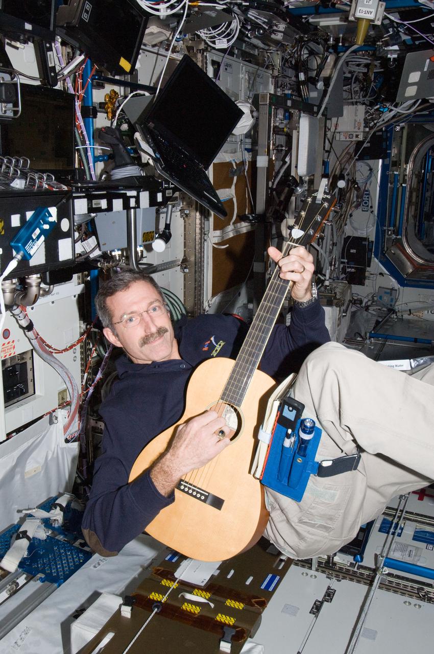 ISS030-E-012631 (16 Dec. 2011) --- NASA astronaut Dan Burbank, Expedition 30 commander, plays a guitar in the Destiny laboratory of the International Space Station.
