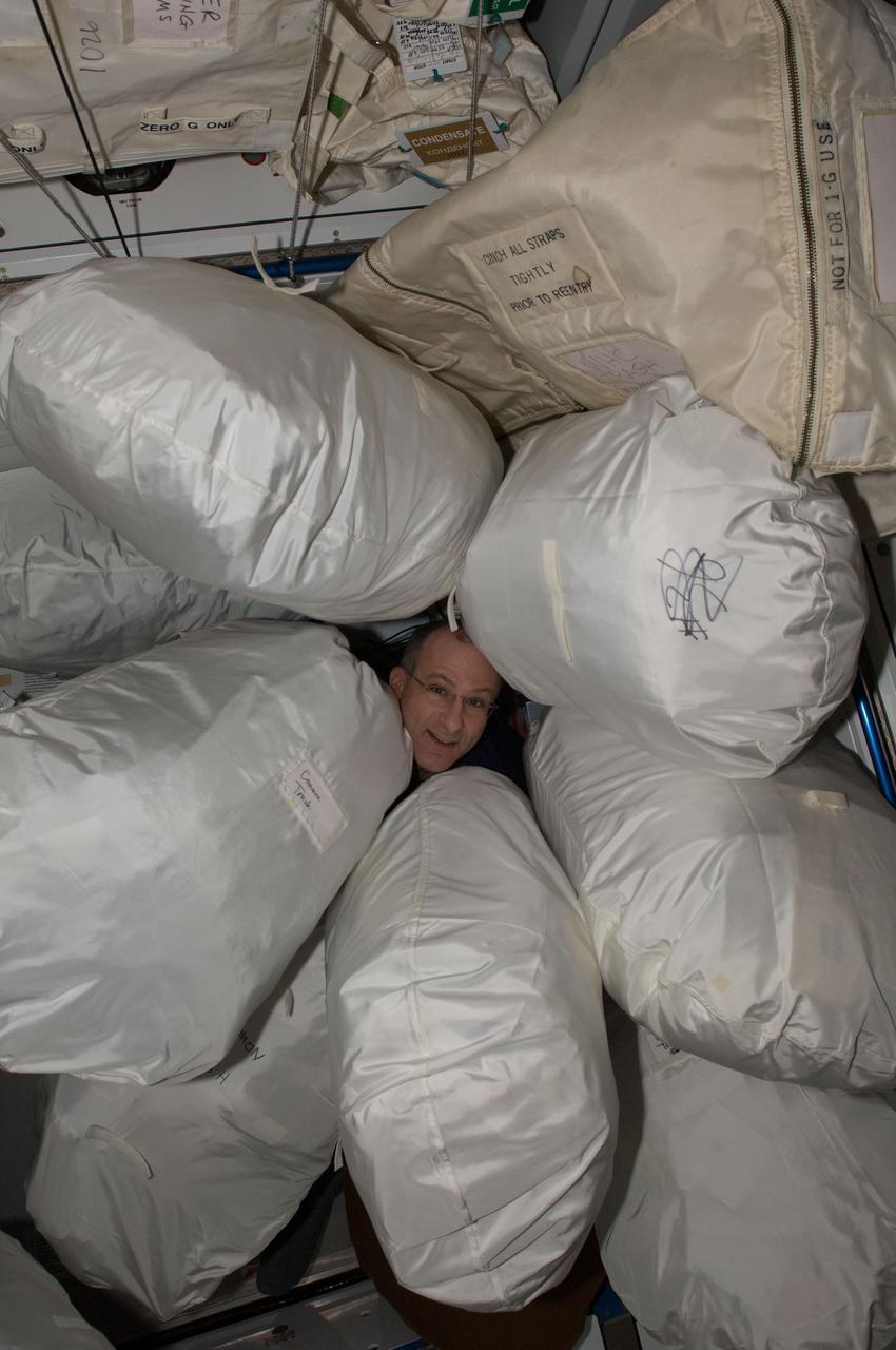 ISS030-E-020706 (4 Jan. 2012) --- NASA astronaut Don Pettit, Expedition 30 flight engineer, is pictured among stowage bags in the Harmony node of the International Space Station. The bags, containing trash and excessed equipment, will be transferred to the docked Progress 45 spacecraft for disposal. The unpiloted ISS Progress 45 supply vehicle is scheduled to undock from the space station on Jan. 24, 2011.