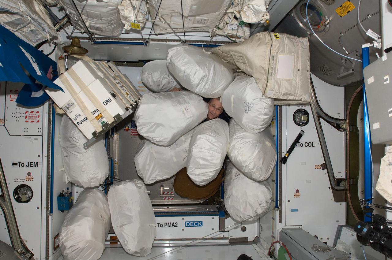 ISS030-E-020707 (4 Jan. 2012) --- NASA astronaut Don Pettit, Expedition 30 flight engineer, is pictured among stowage bags in the Harmony node of the International Space Station. The bags, containing trash and excessed equipment, will be transferred to the docked Progress 45 spacecraft for disposal. The unpiloted ISS Progress 45 supply vehicle is scheduled to undock from the space station on Jan. 24, 2011.