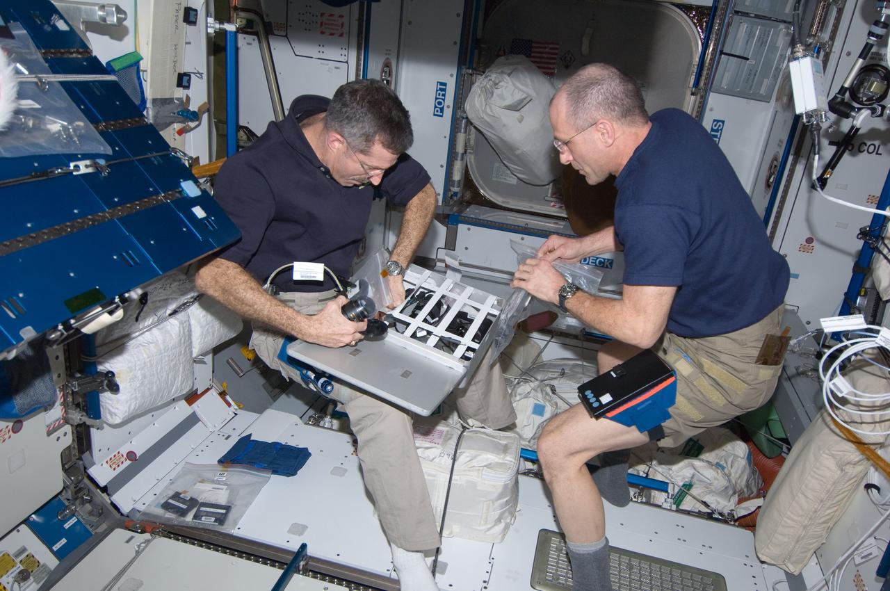 ISS030-E-033351 (25 Dec. 2011) --- NASA astronauts Dan Burbank (left), Expedition 30 commander; and Don Pettit, flight engineer, stow camera equipment in a container in the Harmony node of the International Space Station.