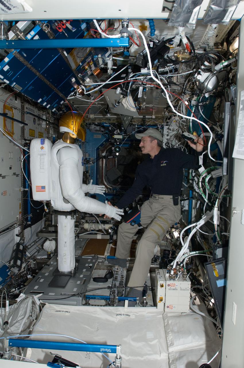 ISS030-E-074063 (15 Feb. 2012) --- Robonaut 2, nicknamed R2, shakes hands with NASA astronaut Dan Burbank, Expedition 30 commander, in the Destiny laboratory of the International Space Station. This event made history with the first human/robotic handshake to be performed in space.