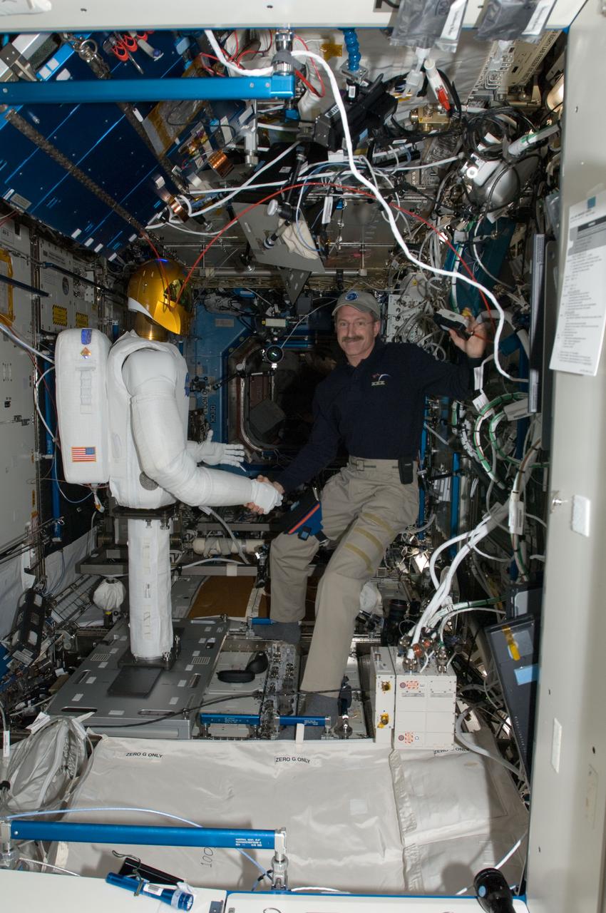 ISS030-E-074065 (15 Feb. 2012) --- Robonaut 2, nicknamed R2, shakes hands with NASA astronaut Dan Burbank, Expedition 30 commander, in the Destiny laboratory of the International Space Station. This event made history with the first human/robotic handshake to be performed in space.