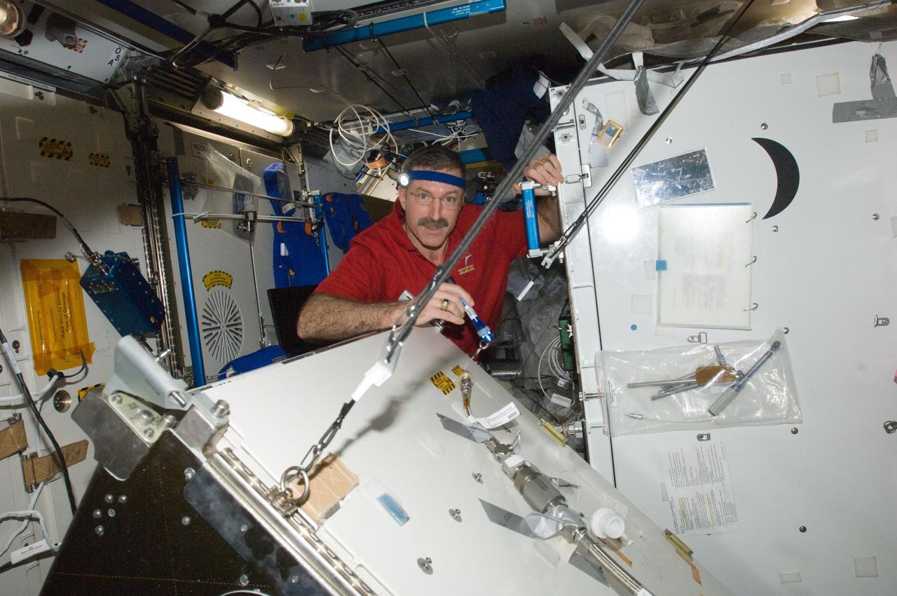 ISS030-E-128752 (8 March 2012) --- NASA astronaut Dan Burbank, Expedition 30 commander, performs part one of the Water Recovery System-1 (WRS-1) repair in the Tranquility node of the International Space Station. Burbank removed and replaced the failed Catalytic Reactor (CR), and installed a temporary filter kit between the new CR and the Microbial Check Valve (MCV) to support a system flush of the new Orbital Replacement Unit (ORU).