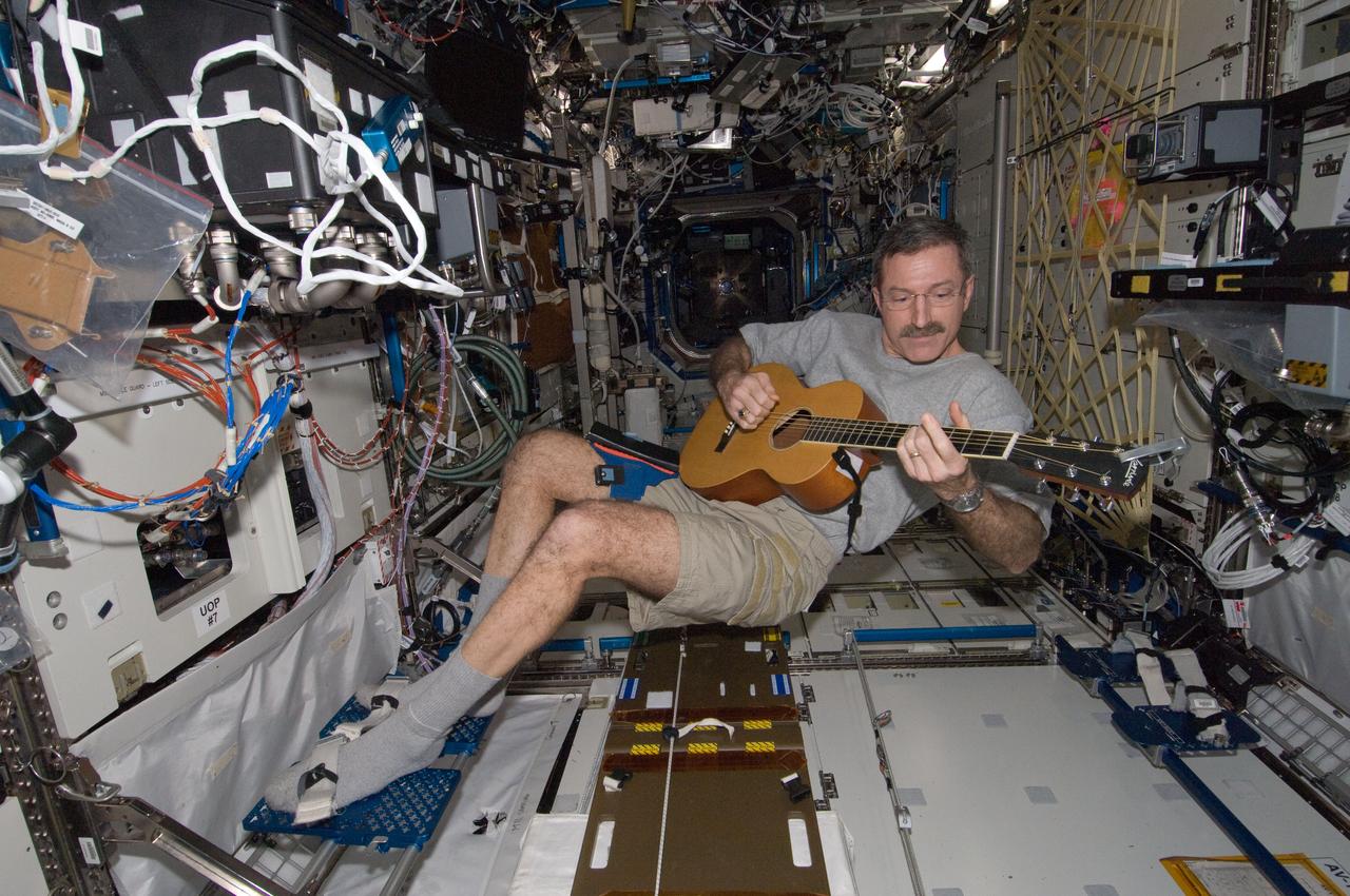 ISS030-E-132618 (10 March 2012) --- NASA astronaut Dan Burbank, Expedition 30 commander, plays a guitar in the Destiny laboratory of the International Space Station.