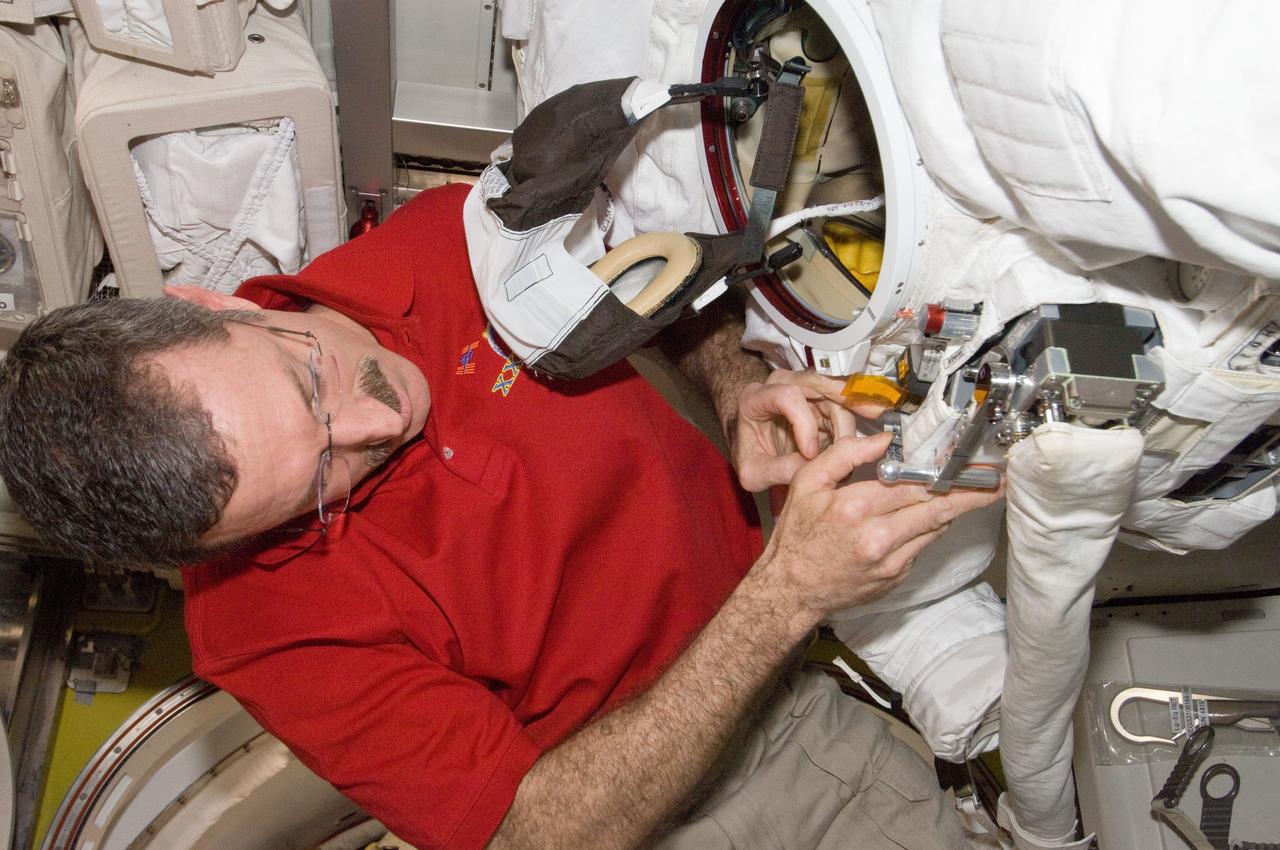 ISS030-E-148280 (13 March 2012) --- NASA astronaut Dan Burbank, Expedition 30 commander, performs routine in-flight maintenance on Extravehicular Mobility Unit (EMU) equipment in the Quest airlock of the International Space Station.