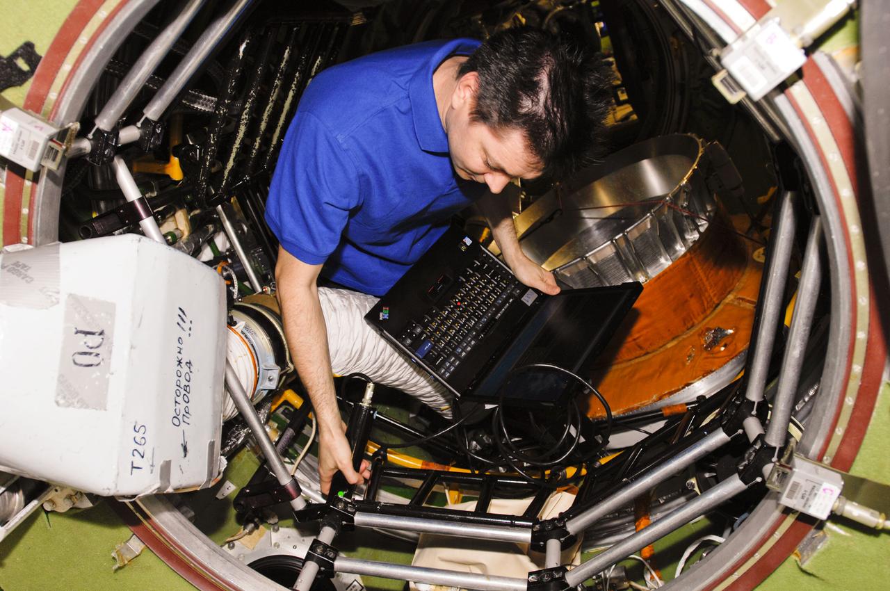 ISS030-E-161169 (21 March 2012) --- Russian cosmonaut Oleg Kononenko, Expedition 30 flight engineer, works in the transfer compartment of the International Space Station?s Zvezda Service Module. Russia's Zarya module is visible in the background.