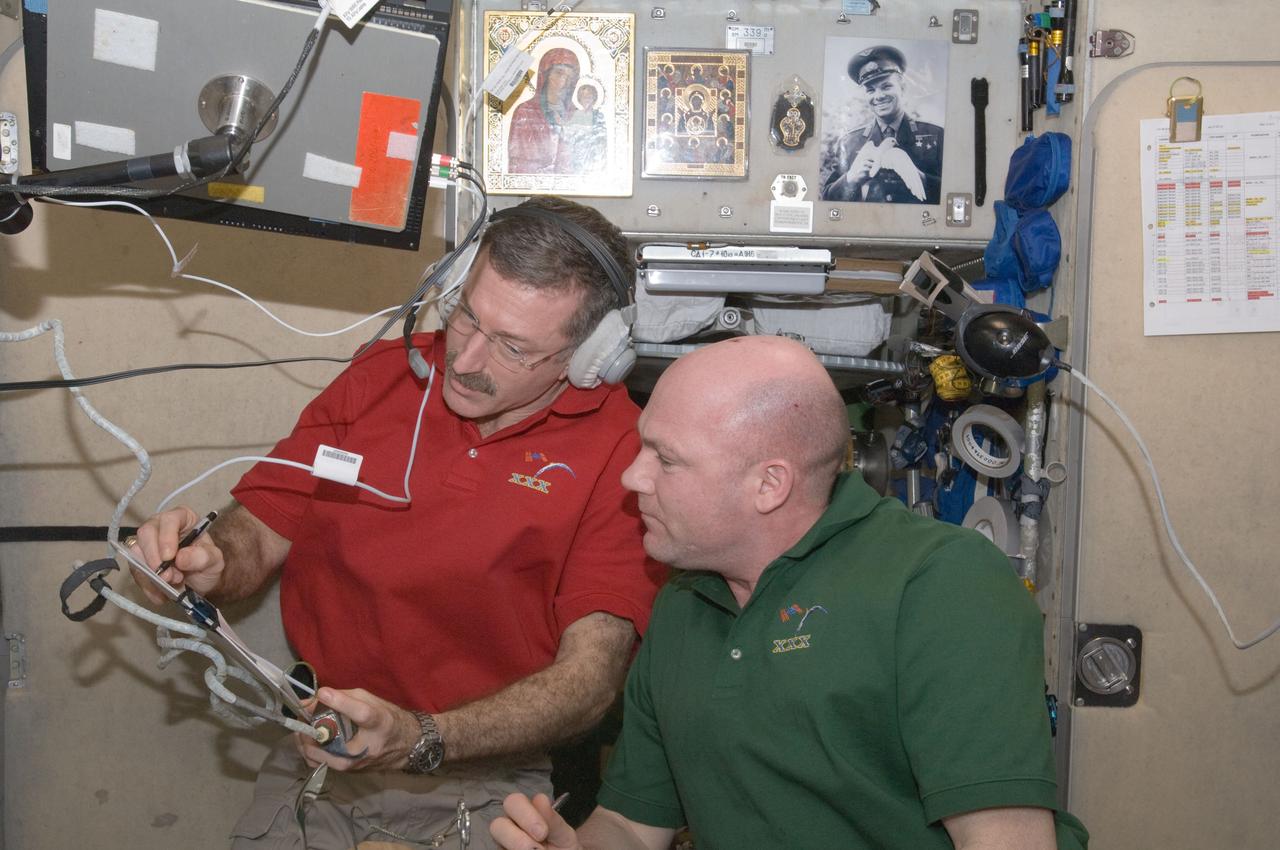 ISS030-E-171113 (24 March 2012) --- NASA astronaut Dan Burbank (wearing a communication headset), Expedition 30 commander; and European Space Agency astronaut Andre Kuipers, flight engineer, review crew procedures in the Zvezda Service Module of the International Space Station in preparation of moving to the appropriate Soyuz vehicles, due to the possibility that space debris could pass close to the station. Burbank, Shkaplerov and Ivanishin sheltered in the Soyuz TMA-22 spacecraft attached to the Poisk Mini-Research Module 2 (MRM2) while Kononenko, Kuipers and Pettit took to the Soyuz TMA-03M docked to the Rassvet Mini-Research Module 1 (MRM-1).