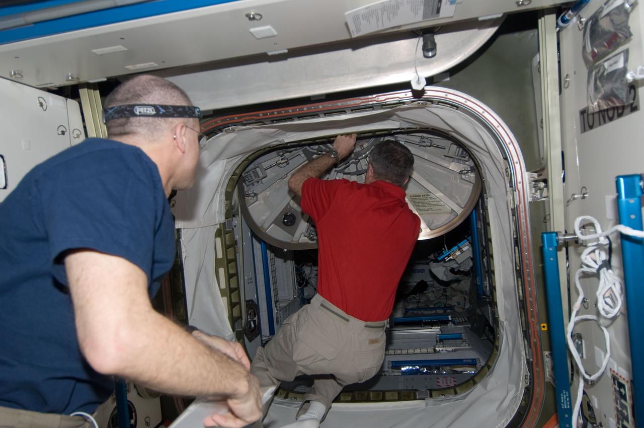 ISS030-E-173920 (24 March 2012) --- NASA astronaut Dan Burbank, Expedition 30 commander, closes a hatch in the International Space Station as crew members prepare to move to the appropriate Soyuz vehicles, due to the possibility that space debris could pass close to the station. NASA astronaut Don Pettit, flight engineer, is at left. Burbank, Shkaplerov and Ivanishin sheltered in the Soyuz TMA-22 spacecraft attached to the Poisk Mini-Research Module 2 (MRM2) while Kononenko, Kuipers and Pettit took to the Soyuz TMA-03M docked to the Rassvet Mini-Research Module 1 (MRM-1).