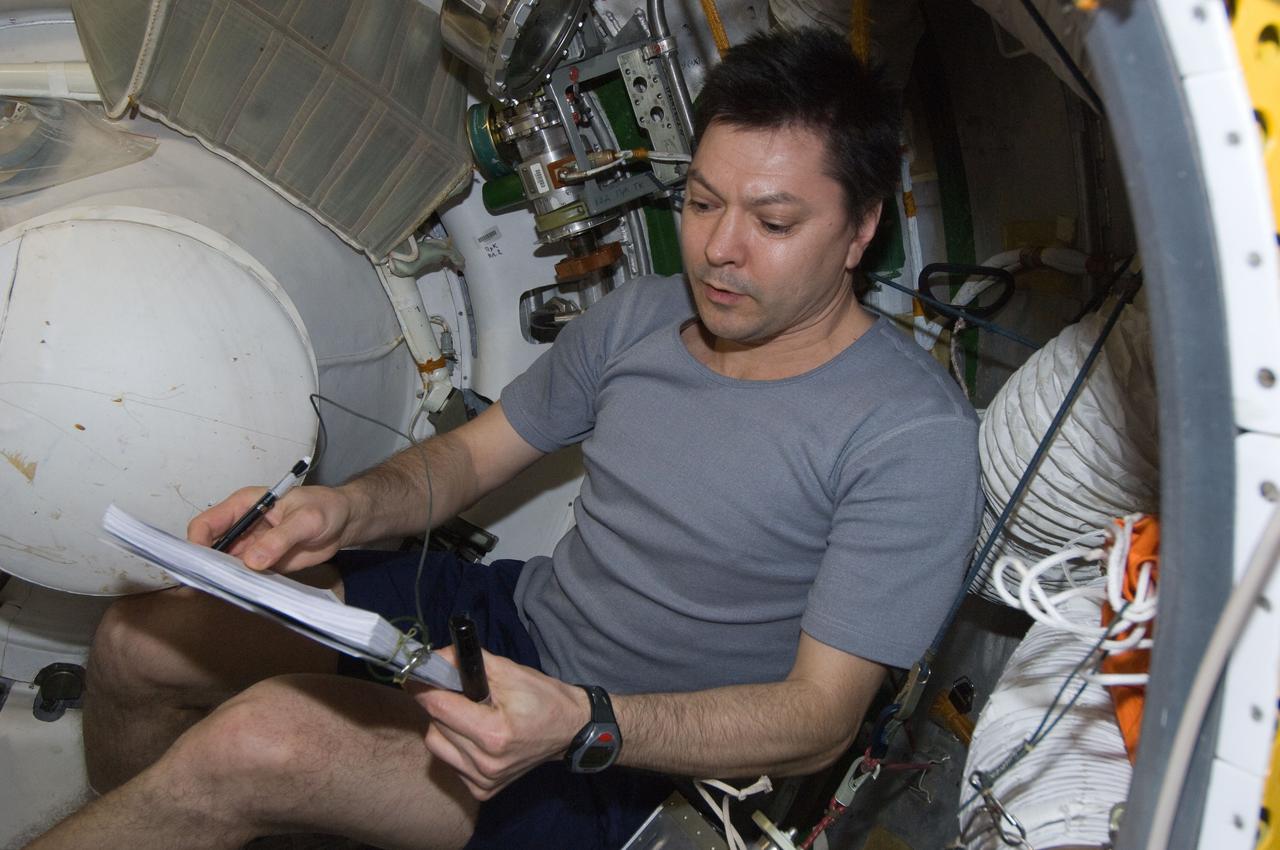 ISS030-E-177375 (29 March 2012) --- Russian cosmonaut Oleg Kononenko, Expedition 30 flight engineer, reviews a procedures checklist while conducting a leak check in the Zvezda Service Module transfer tunnel/ATV vestibule of the International Space Station.