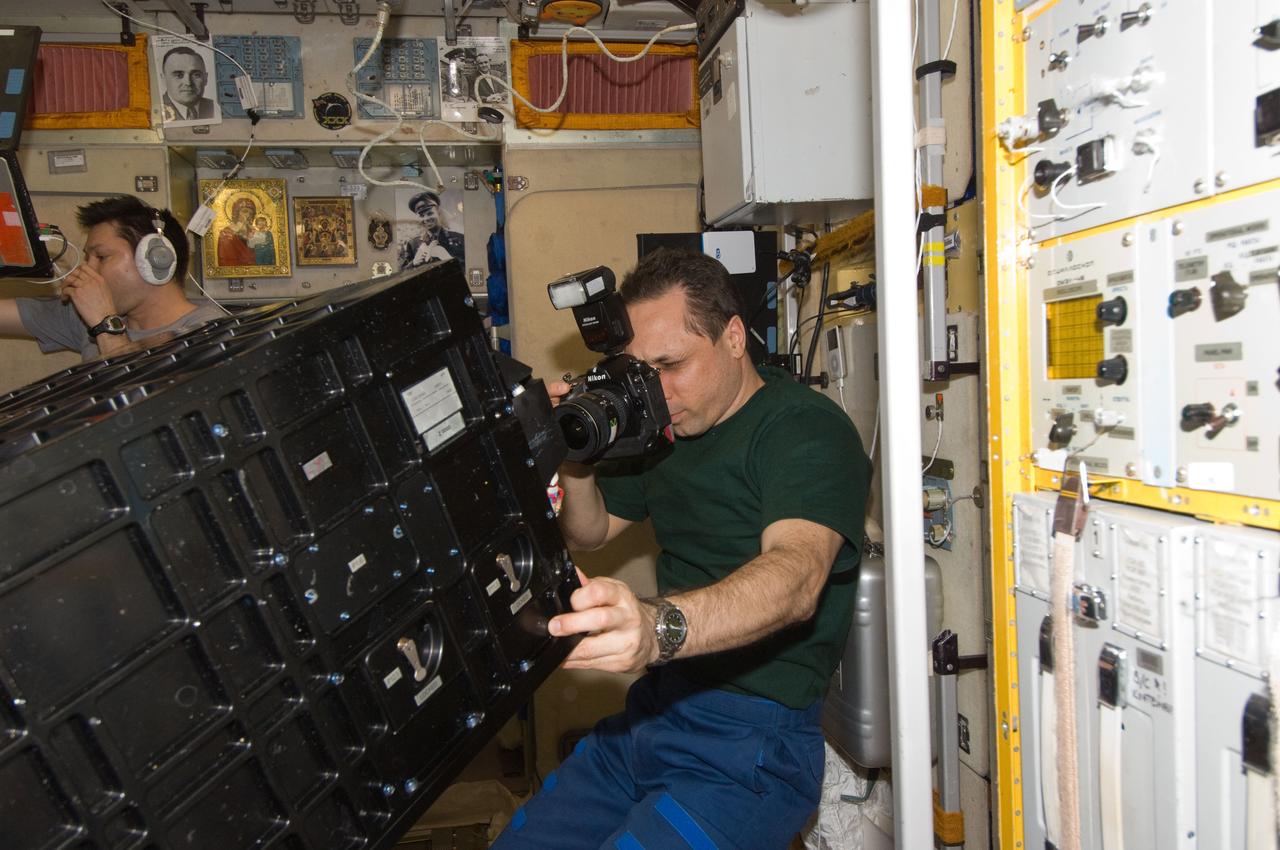 ISS030-E-177376 (29 March 2012) --- In the International Space Station?s Zvezda Service Module, Russian cosmonaut Anton Shkaplerov, Expedition 30 flight engineer, uses a still camera for photo documentation of the Proximity Communications Equipment (PCE) which was used for the ATV-3 rendezvous and docking. Russian cosmonaut Oleg Kononenko, flight engineer, is visible in the background.