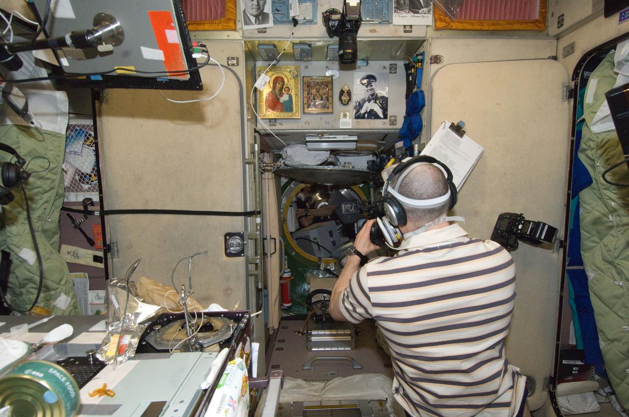 ISS030-E-177715 (29 March 2012) --- In the International Space Station?s Zvezda Service Module, Russian cosmonaut Anatoly Ivanishin, Expedition 30 flight engineer, uses a video camera as his crewmates prepare to open the hatch to European Space Agency?s ?Edoardo Amaldi? Automated Transfer Vehicle-3 (ATV-3). The ATV docked with the space station on March 28, 2012.
