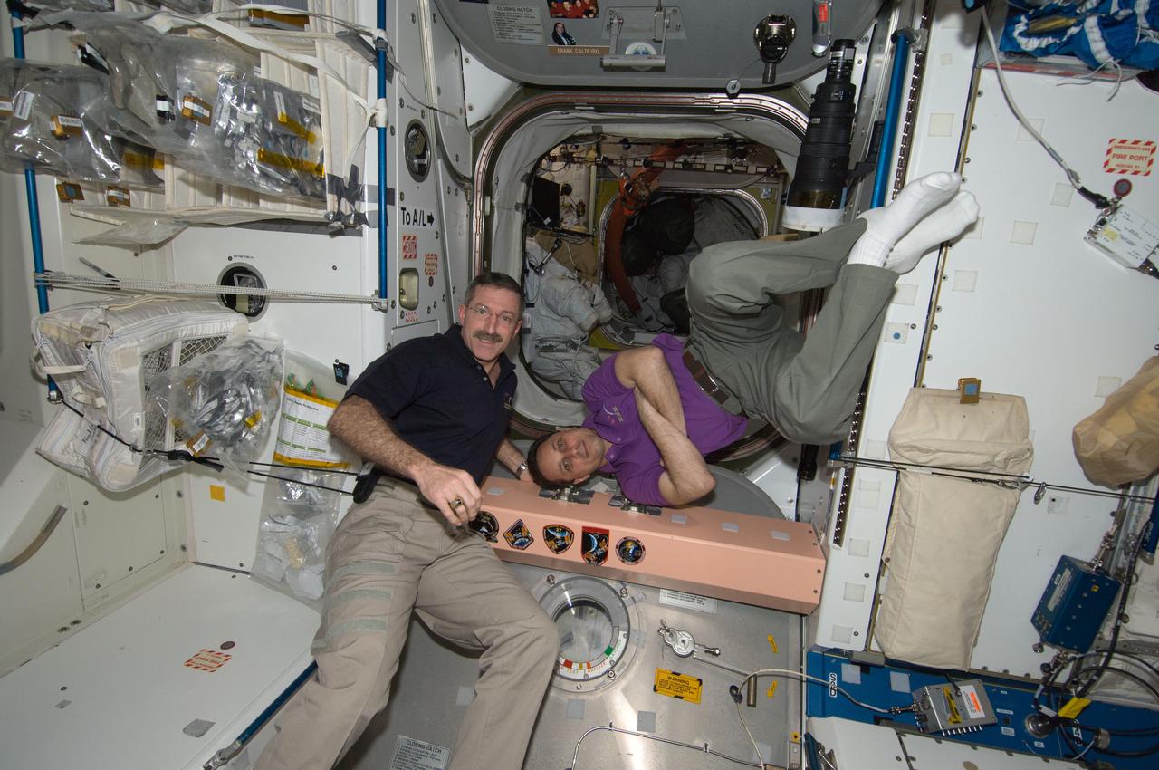 ISS030-E-241316 (21 April 2012) --- In the Unity node, NASA astronaut Dan Burbank (left), Expedition 30 commander; and Russian cosmonaut Anton Shkaplerov, flight engineer, are pictured near a growing collection of insignias representing crews who have worked on the International Space Station.