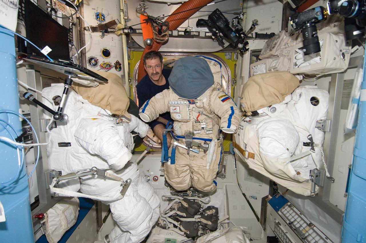ISS030-E-247076 (7 April 2012) --- NASA astronaut Dan Burbank, Expedition 30 commander, is pictured with a Russian Orlan spacesuit between two Extravehicular Mobility Unit (EMU) spacesuits in the Quest airlock of the International Space Station.