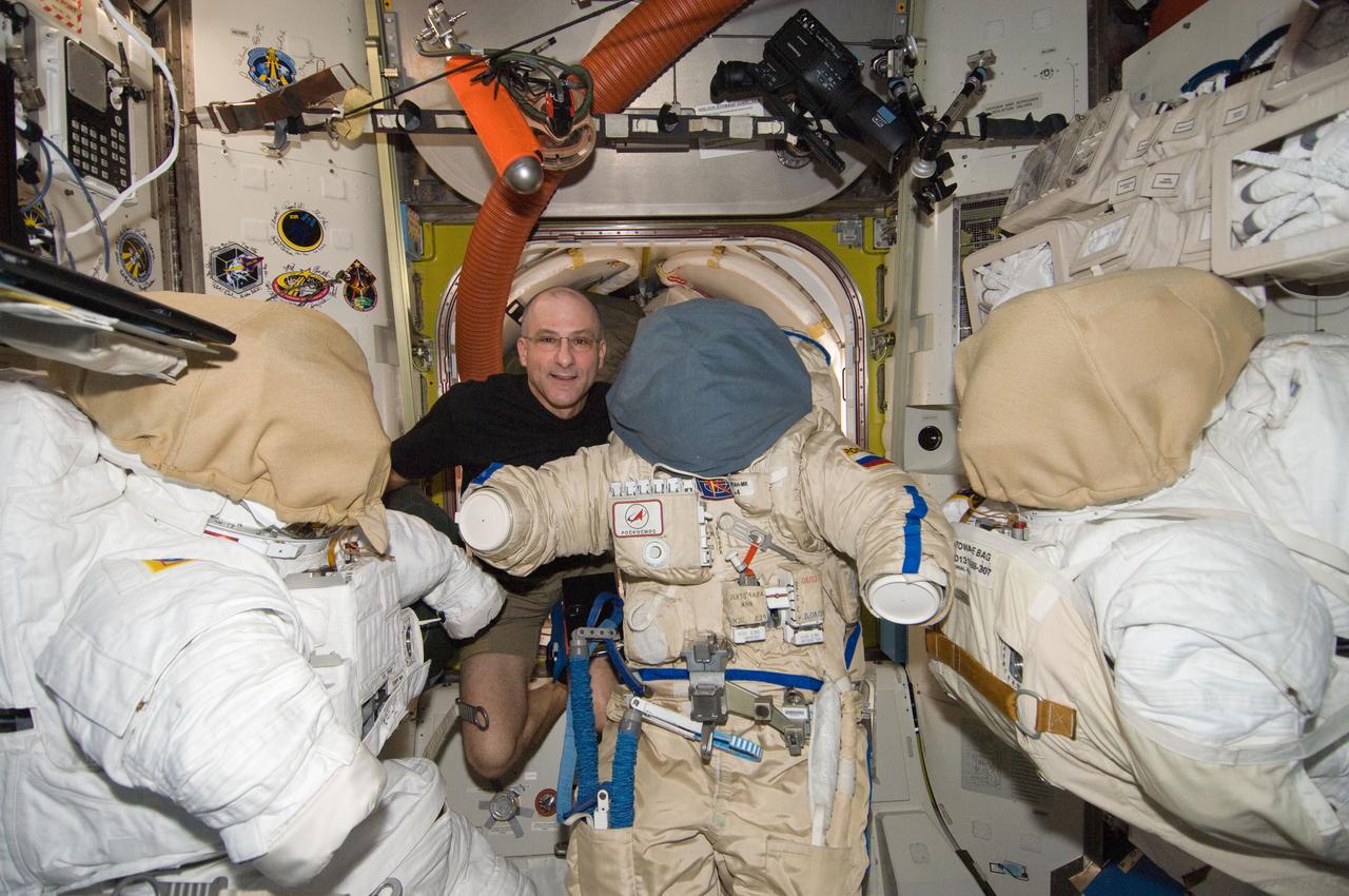 ISS030-E-247080 (7 April 2012) --- NASA astronaut Don Pettit, Expedition 30 flight engineer, is pictured with a Russian Orlan spacesuit between two Extravehicular Mobility Unit (EMU) spacesuits in the Quest airlock of the International Space Station.