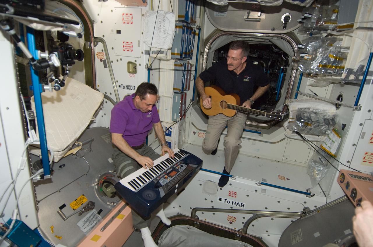 ISS030-E-267651 (21 April 2012) --- NASA astronaut Dan Burbank, Expedition 30 commander, plays a guitar, while Russian cosmonaut Anton Shkaplerov, flight engineer, plays a musical keyboard during off-time in the Unity node of the International Space Station.