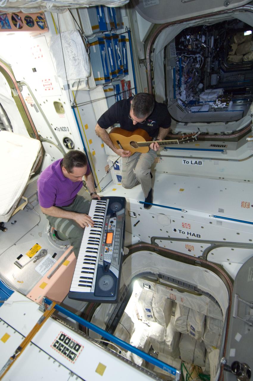 ISS030-E-267658 (21 April 2012) --- NASA astronaut Dan Burbank, Expedition 30 commander, plays a guitar, while Russian cosmonaut Anton Shkaplerov, flight engineer, plays a musical keyboard during off-time in the Unity node of the International Space Station.