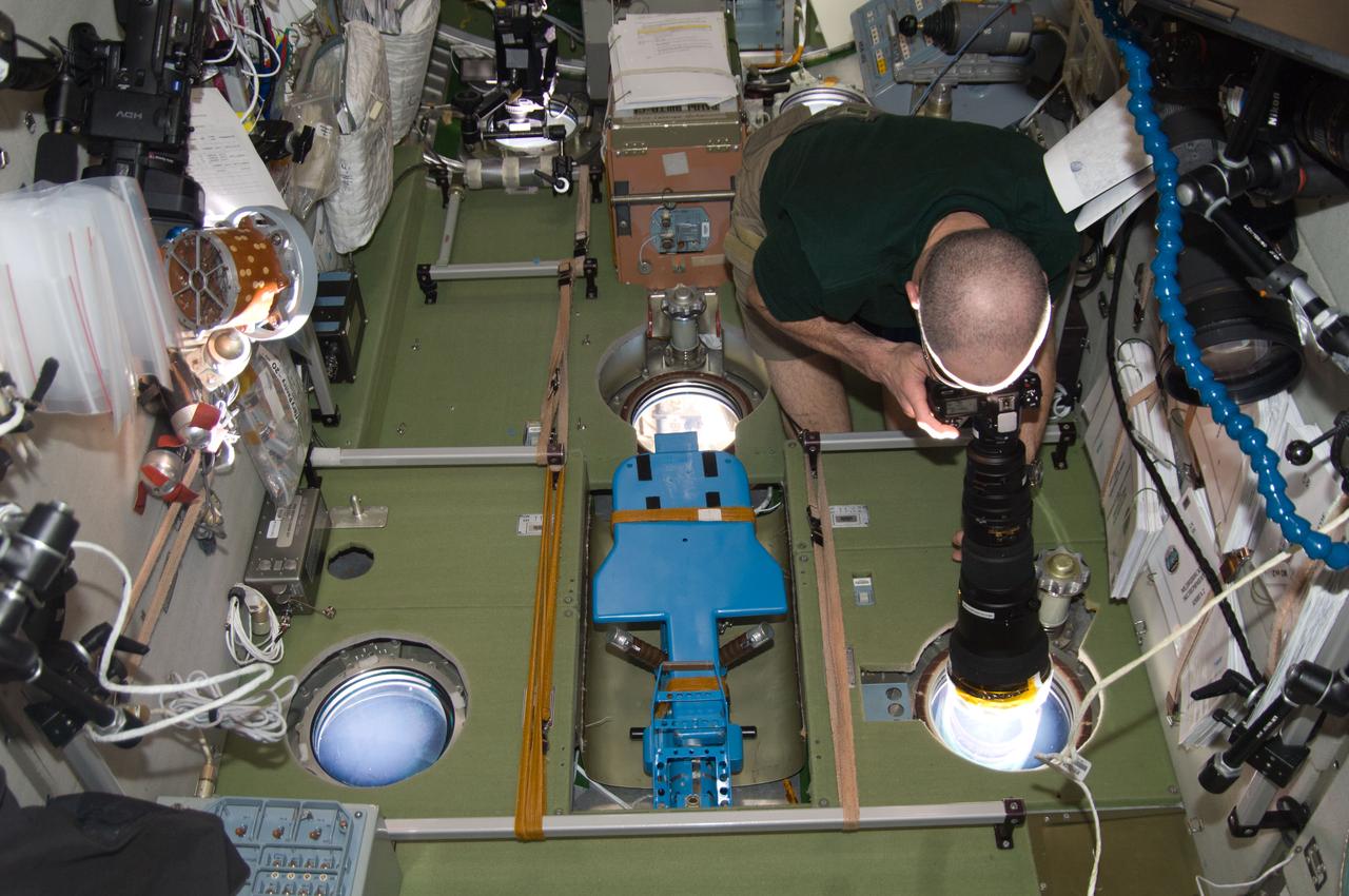 ISS031-E-005786 (27 April 2012) --- NASA astronaut Don Pettit, Expedition 31 flight engineer, uses a still camera at a window in the Zvezda Service Module of the International Space Station to photograph the departure of the Soyuz TMA-22 spacecraft carrying Expedition 30 crew members back to Earth.