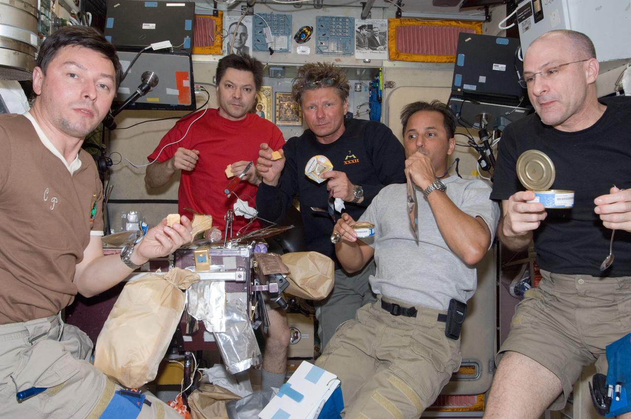 ISS031-E-041675 (18 May 2012) --- Expedition 31 crew members share a meal near the galley in the Zvezda Service Module of the International Space Station. Pictured from the left are Russian cosmonauts Sergei Revin, flight engineer; Oleg Kononenko, commander; and Gennady Padalka, flight engineer; along with NASA astronauts Joe Acaba and Don Pettit, both flight engineers. Out of frame is European Space Agency astronaut Andre Kuipers, flight engineer.