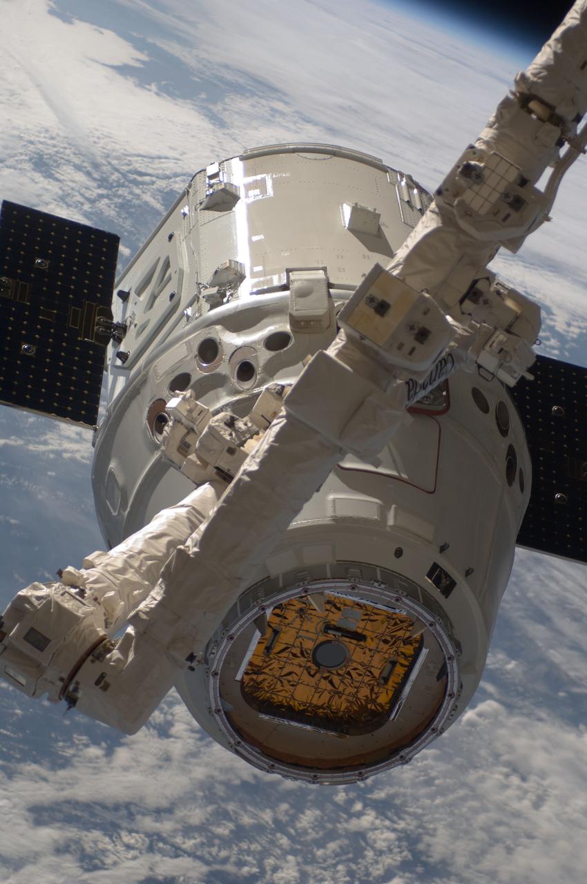 ISS031-E-071199 (25 May 2012) --- With clouds over Earth forming a backdrop, the SpaceX Dragon commercial cargo craft is photographed during grappling operations with the Canadarm2 robotic arm at the International Space Station. Expedition 31 Flight Engineers Don Pettit and Andre Kuipers grappled Dragon at 9:56 a.m. (EDT) and used the robotic arm to berth Dragon to the Earth-facing side of the station's Harmony node at 12:02 p.m. May 25, 2012. Dragon became the first commercially developed space vehicle to be launched to the station to join Russian, European and Japanese resupply craft that service the complex while restoring a U.S. capability to deliver cargo to the orbital laboratory. Dragon is scheduled to spend about a week docked with the station before returning to Earth on May 31 for retrieval.