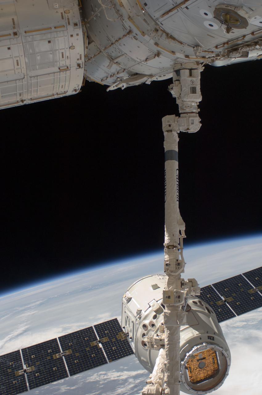 ISS031-E-071203 (25 May 2012) --- With the blackness of space and clouds over Earth forming a backdrop, the SpaceX Dragon commercial cargo craft is grappled by the Canadarm2 robotic arm at the International Space Station. Expedition 31 Flight Engineers Don Pettit and Andre Kuipers grappled Dragon at 9:56 a.m. (EDT) and used the robotic arm to berth Dragon to the Earth-facing side of the station's Harmony node at 12:02 p.m. May 25, 2012. Dragon became the first commercially developed space vehicle to be launched to the station to join Russian, European and Japanese resupply craft that service the complex while restoring a U.S. capability to deliver cargo to the orbital laboratory. Dragon is scheduled to spend about a week docked with the station before returning to Earth on May 31 for retrieval.