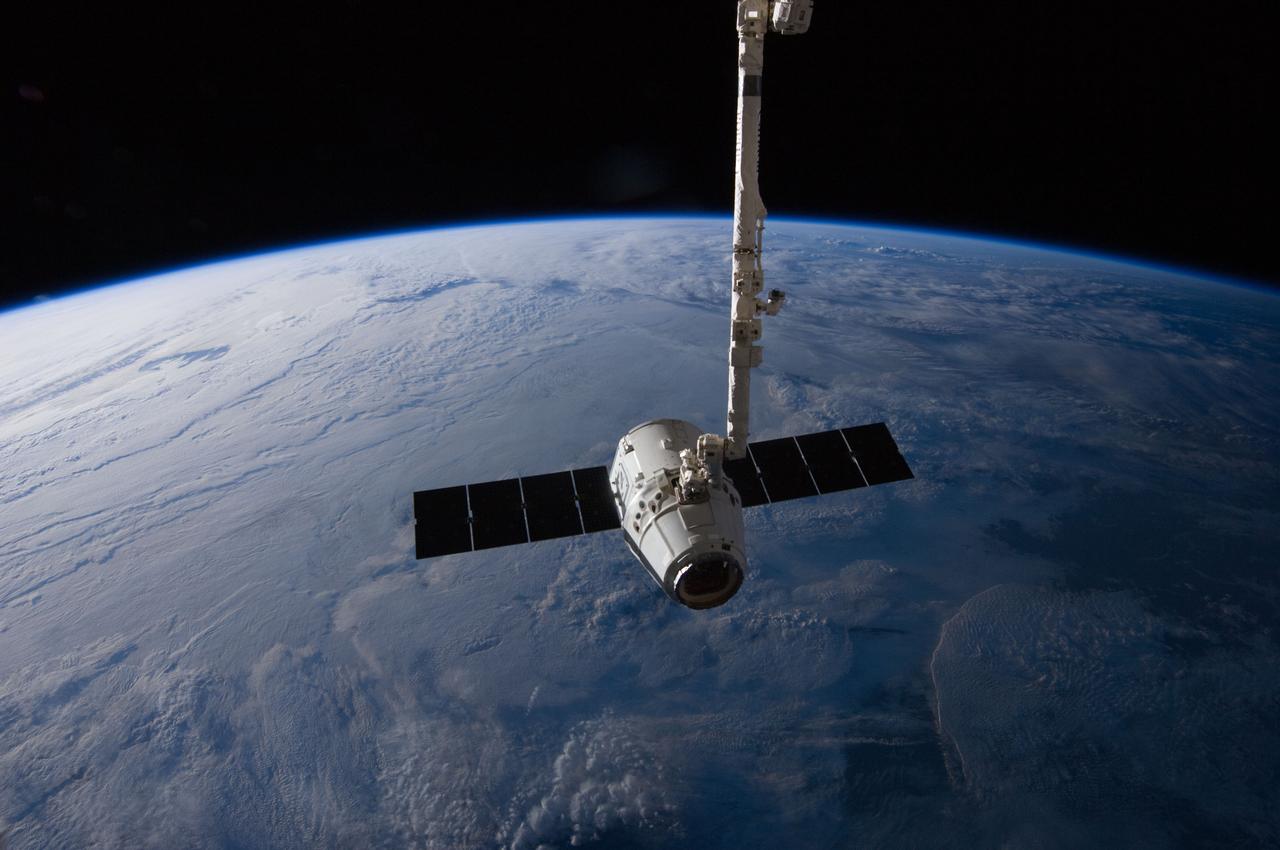 ISS031-E-079332 (31 May 2012) --- The SpaceX Dragon cargo craft, after spending the better part of a week docked to the International Space Station, is suspended in the grasp of the Candarm2 robotic arm some 240 miles above the home planet prior to its May 31 return.