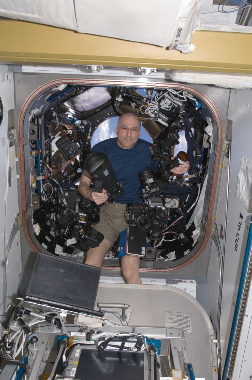 ISS031-E-112469 (10 June 2012) --- NASA astronaut Don Pettit, Expedition 31 flight engineer, poses with several still cameras in the Cupola of the International Space Station.