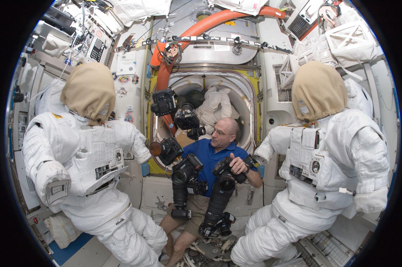 ISS031-E-112512 (10 June 2012) --- A fisheye lens attached to an electronic still camera was used to capture this image of NASA astronaut Don Pettit, Expedition 31 flight engineer, as he works with still camera equipment in the Quest airlock of the International Space Station, while flanked by a pair of NASA Extravehicular Mobility Unit (EMU) spacesuits.