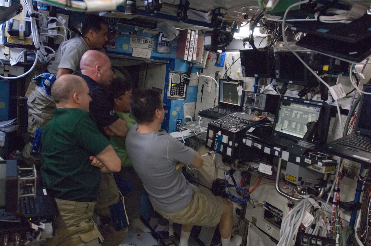 ISS031-E-140385 (22 May 2012) --- Expedition 31 crew members watch the launch of the SpaceX Falcon 9 rocket on a computer monitor in the Destiny laboratory of the International Space Station on May 22, 2012. Pictured clockwise (from bottom right) are Russian cosmonaut Oleg Kononenko, commander; NASA astronaut Don Pettit, European Space Agency astronaut Andre Kuipers, NASA astronaut Joe Acaba, Russian cosmonauts Sergei Revin (obscured) and Gennady Padalka, all flight engineers.