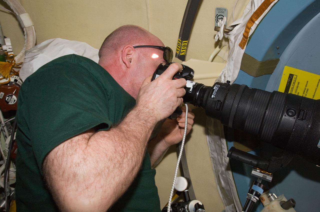 ISS031-E-144352 (5 June 2012) --- European Space Agency astronaut Andre Kuipers, Expedition 31 flight engineer, uses a still camera at a window on the International Space Station.