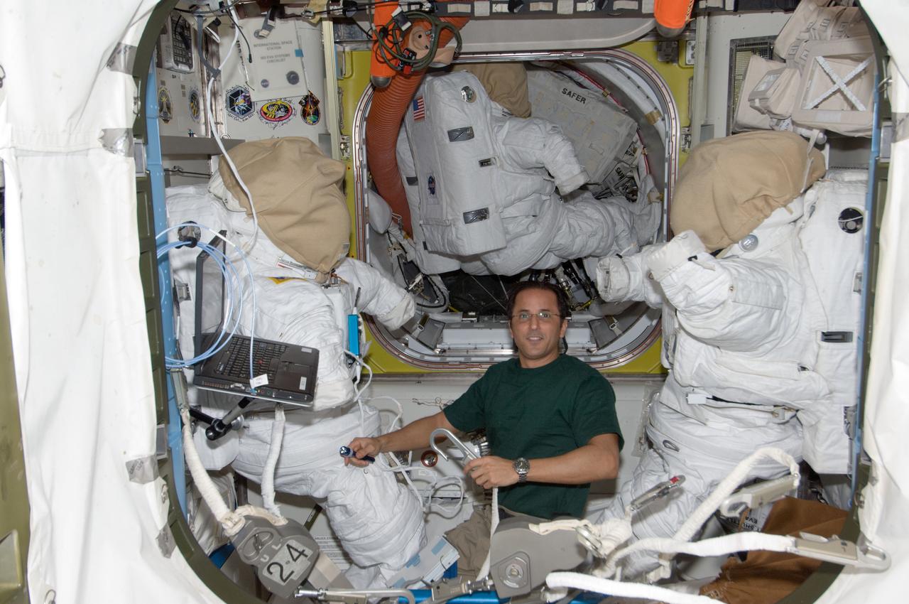 ISS032-E-006433 (9 July 2012) --- NASA astronaut Joe Acaba, Expedition 32 flight engineer, works with extravehicular activity (EVA) equipment between two Extravehicular Mobility Unit (EMU) spacesuits in the Quest airlock of the International Space Station.