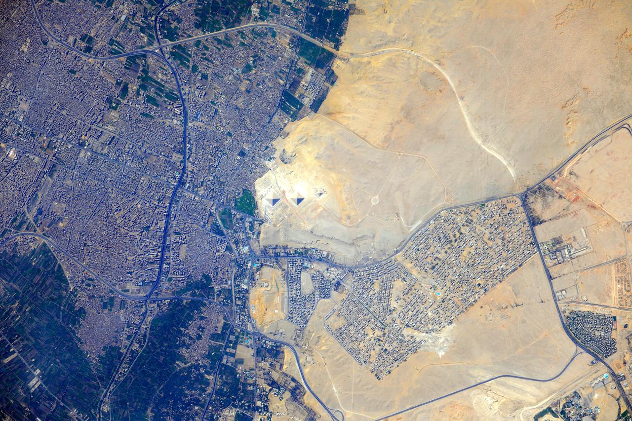 ISS032-E-009123 (26 July 2012) --- Pyramids at Giza, Egypt are featured in this image photographed by an Expedition 32 crew member on the International Space Station. The Great Pyramids at Giza (center) are the last of the Seven Wonders of the Ancient World, and are perhaps the most famous of the ancient monuments in the Nile River Delta region of Egypt. They are also a favorite subject of photography from orbit ? particularly when high resolution imagery can be obtained. The southeast-facing sides of the pyramids of the pharaohs Khufu, Khafre, and Menkaure are all brightly illuminated by the sun, while the northwest facing sides are in shadow. This shadowing also highlights smaller unfinished pyramids to the south of Menkaure?s pyramid, as well as fields of rectangular flat roofed mastabas (tombs) to the east and west of Khufu?s pyramid. While not as grand as the pyramids, mastabas were the burial places of prominent persons during the periods of the ancient pharaohs. To the southeast of Khufu?s pyramid, the head and rear haunches of the Sphinx are also visible (albeit not clearly). It is a short distance between the glories of ancient Egypt and the modern Cairo metropolitan area to the north and east. The green vegetation of a hotel golf course (center left), and the numerous building and streets of El Giza, provide stark contrast to the bare rock and soil of the adjacent desert. Roadways visible in the desert (right) connect the urban regions to the east with further development to the north.