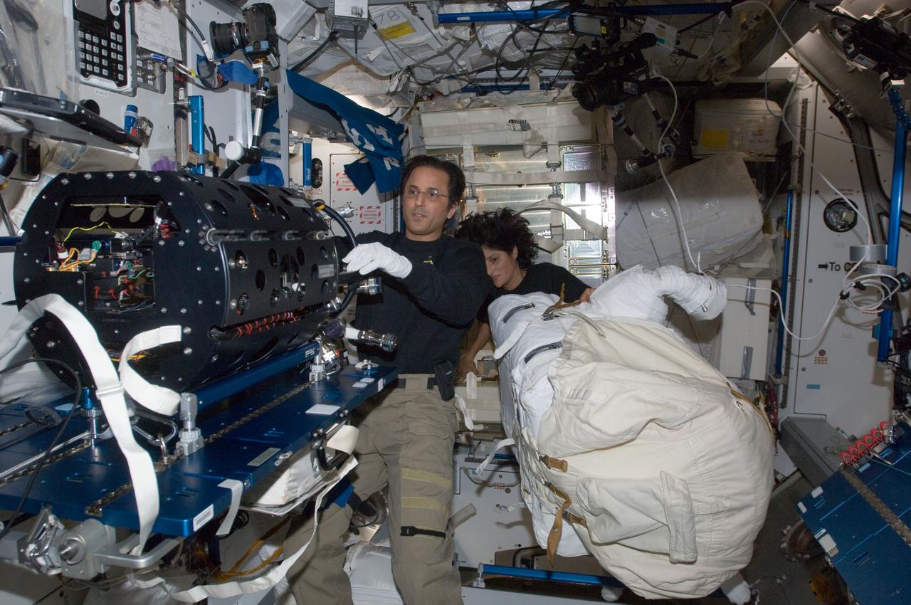ISS032-E-016863 (7 Aug. 2012) --- NASA astronaut Joe Acaba, Expedition 32 flight engineer, works on the Multi-User Droplet Combustion Apparatus (MDCA) Chamber Insert Assembly (CIA) in the Harmony node of the International Space Station. NASA astronaut Sunita Williams, flight engineer, works with an Extravehicular Mobility Unit (EMU) spacesuit in the background.