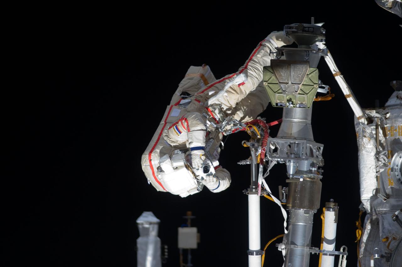 ISS032-E-021072 (20 Aug. 2012) --- Russian cosmonaut Gennady Padalka, Expedition 32 commander, uses a still camera during a session of extravehicular activity (EVA) to continue outfitting the International Space Station. During the five-hour, 51-minute spacewalk, Padalka and Russian cosmonaut Yuri Malenchenko (out of frame), flight engineer, moved the Strela-2 cargo boom from the Pirs docking compartment to the Zarya module to prepare Pirs for its eventual replacement with a new Russian multipurpose laboratory module. The two spacewalking cosmonauts also installed micrometeoroid debris shields on the exterior of the Zvezda service module and deployed a small science satellite.