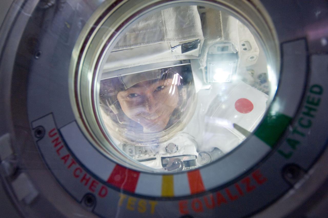 ISS032-E-024401 (30 Aug. 2012) --- Japan Aerospace Exploration Agency astronaut Aki Hoshide, Expedition 32 flight engineer, attired in an Extravehicular Mobility Unit (EMU) spacesuit, looks through a hatch window in the Quest airlock of the International Space Station prior to a session of extravehicular activity (EVA).