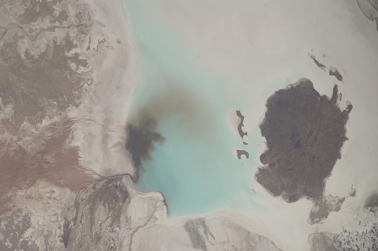 ISS033-E-006202 (20 Sept. 2012) --- Salar de Coipasa, Bolivia is featured in this image photographed by an Expedition 33 crew member on the International Space Station. The Salar de Coipasa, located in the Altiplano region of western Bolivia, covers an area of approximately 2,500 square kilometers. The word ?salar? describes arid closed basins in which evaporation of mineral-rich waters leads to the formation of thick, flat-laying salt deposits. Salar de Coipasa is located to the southwest of the saline Lake Poopo and northwest of the largest salt flat in the world, Salar de Uyuni. At Coipasa, a crust composed of halite?common table salt?provides the brilliant white coloration characteristic of the Altiplano salars (right). While the environment of Salar de Coipasa is arid, it does receive constant water from the Lauca River flowing from the north; this feeds Lake (Lago) Coipasa that fills the northern end of the basin with shallow water (center). However, the water flow can drop off sharply during periods of drought. The waters of Lake Coipasa, and the white salt crust of the salar, also serve to highlight dark river sediments flowing into the basin along the northeastern shore. Dark volcanic rocks contrast sharply with the surrounding salt crust at right. While the western Andes Mountains contain many active volcanoes, the nearby Tata Sabaya volcano has not been historically active.