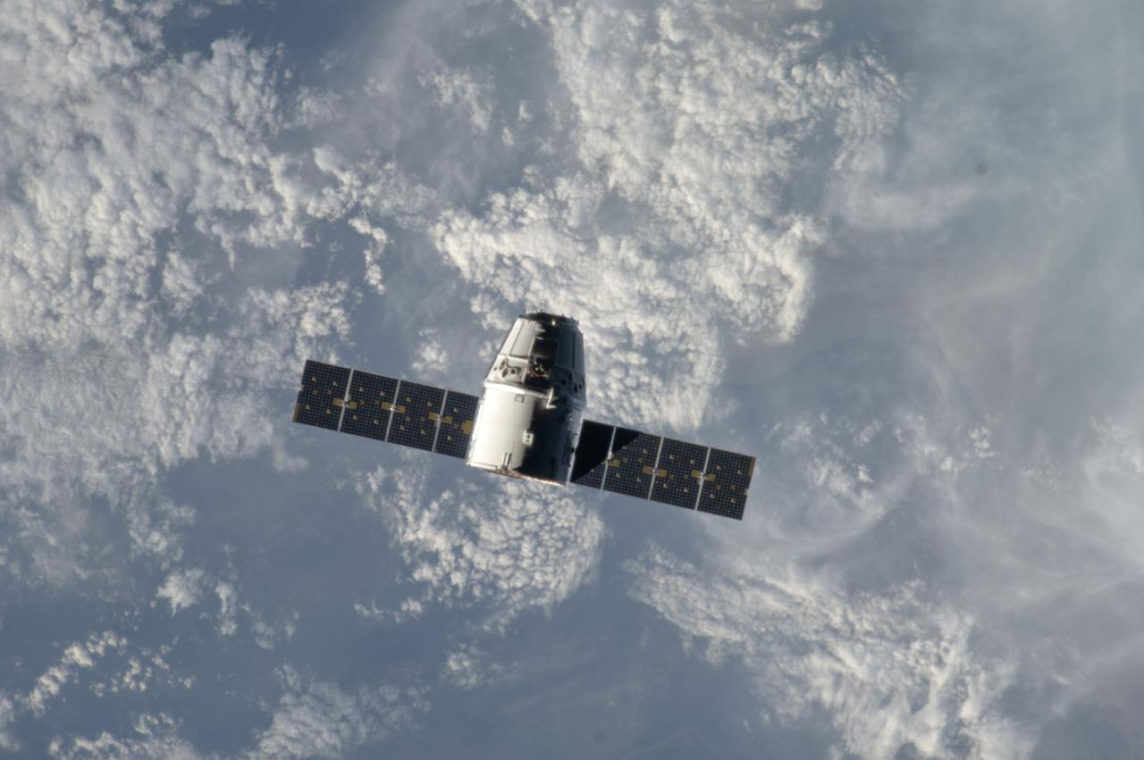 ISS033-E-011381 (10 Oct. 2012) --- Backdropped by a cloud-covered part of Earth, the SpaceX Dragon commercial cargo craft makes its relative approach to the International Space Station prior to grapple by the station?s Canadarm2 robotic arm, controlled by Expedition 33 crew members.