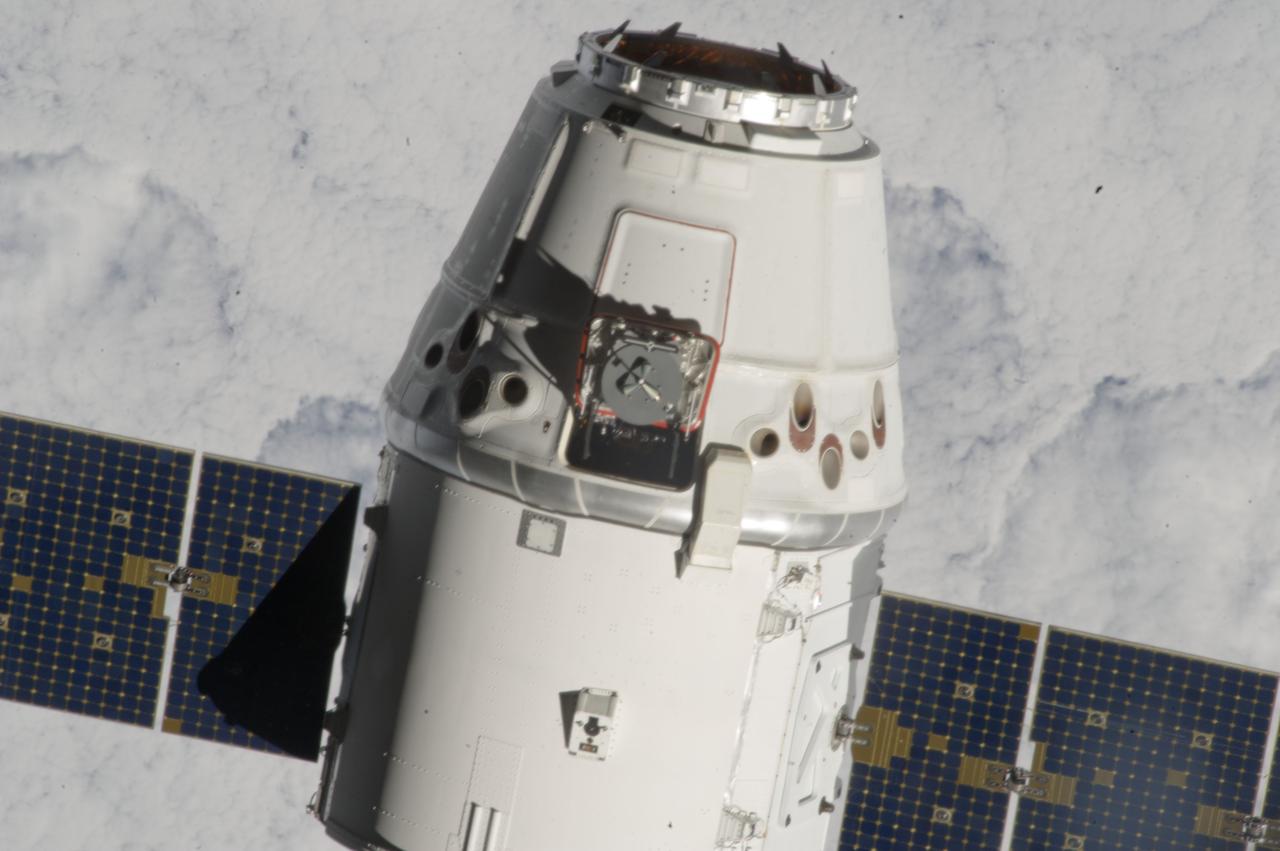 ISS033-E-011554 (10 Oct. 2012) --- Backdropped by a cloud-covered part of Earth, the SpaceX Dragon commercial cargo craft makes its relative approach to the International Space Station prior to grapple by the station’s Canadarm2 robotic arm, controlled by Expedition 33 crew members.