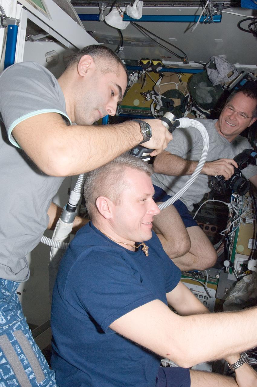 ISS033-E-018986 (10 Nov. 2012) --- Russian cosmonaut Evgeny Tarelkin, Expedition 33 flight engineer, trims the hair of Russian cosmonaut Oleg Novitskiy, flight engineer, in the Tranquility node of the International Space Station. Tarelkin used hair clippers fashioned with a vacuum device to garner freshly cut hair. NASA astronaut Kevin Ford, flight engineer, is visible in the background.