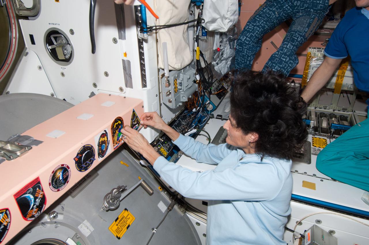 ISS033-E-022049 (17 Nov. 2012) --- In the Unity node, NASA astronaut Sunita Williams, Expedition 33 commander, adds the Expedition 33 patch to the growing collection of insignias representing crews who have worked on the International Space Station, following the ceremony of Changing-of-Command from Expedition 33 to Expedition 34.