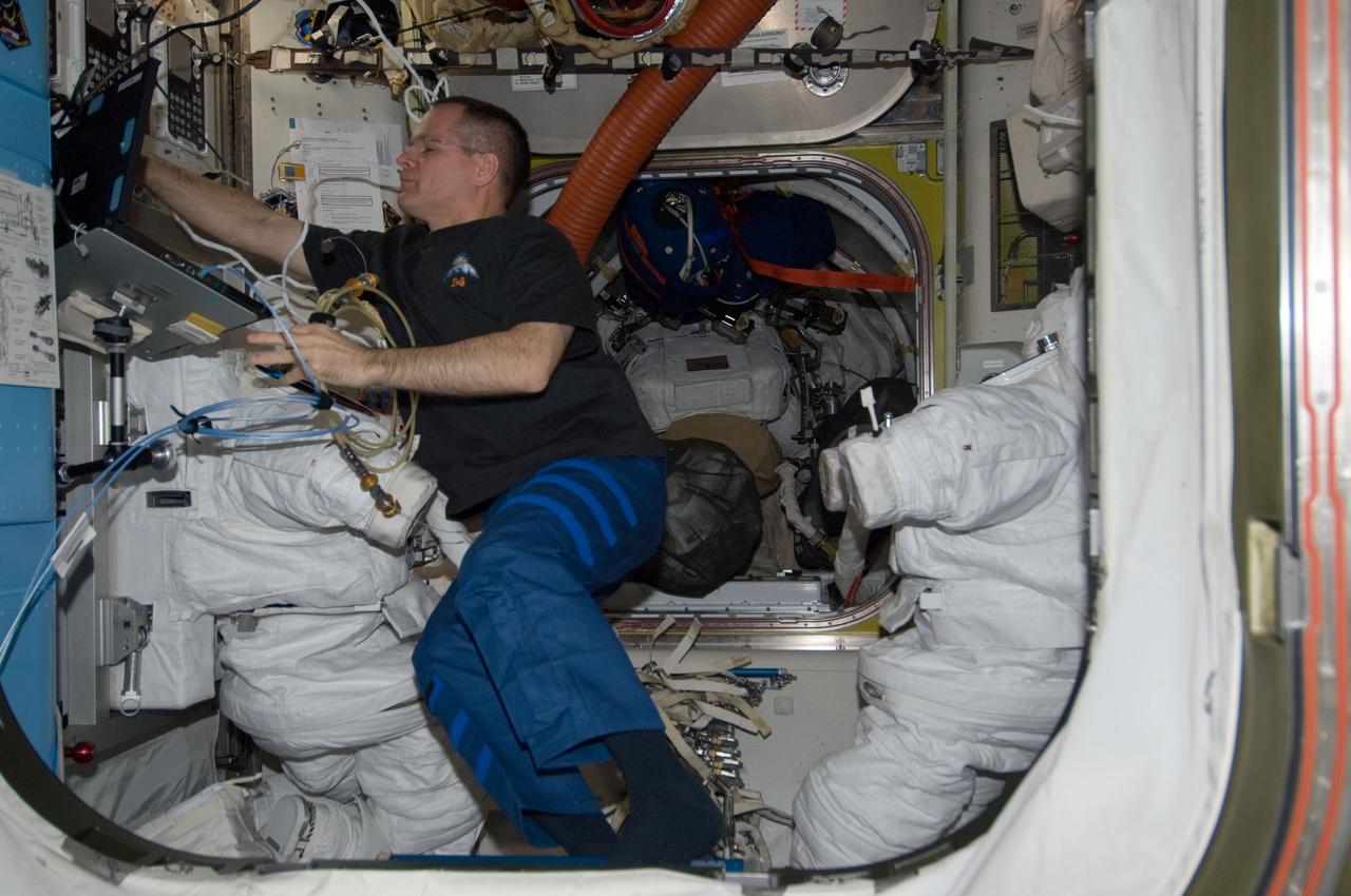 ISS034-E-005621 (5 Dec. 2012) --- NASA astronaut Kevin Ford, Expedition 34 commander, uses a computer near two Extravehicular Mobility Unit (EMU) spacesuits in the Quest airlock of the International Space Station.