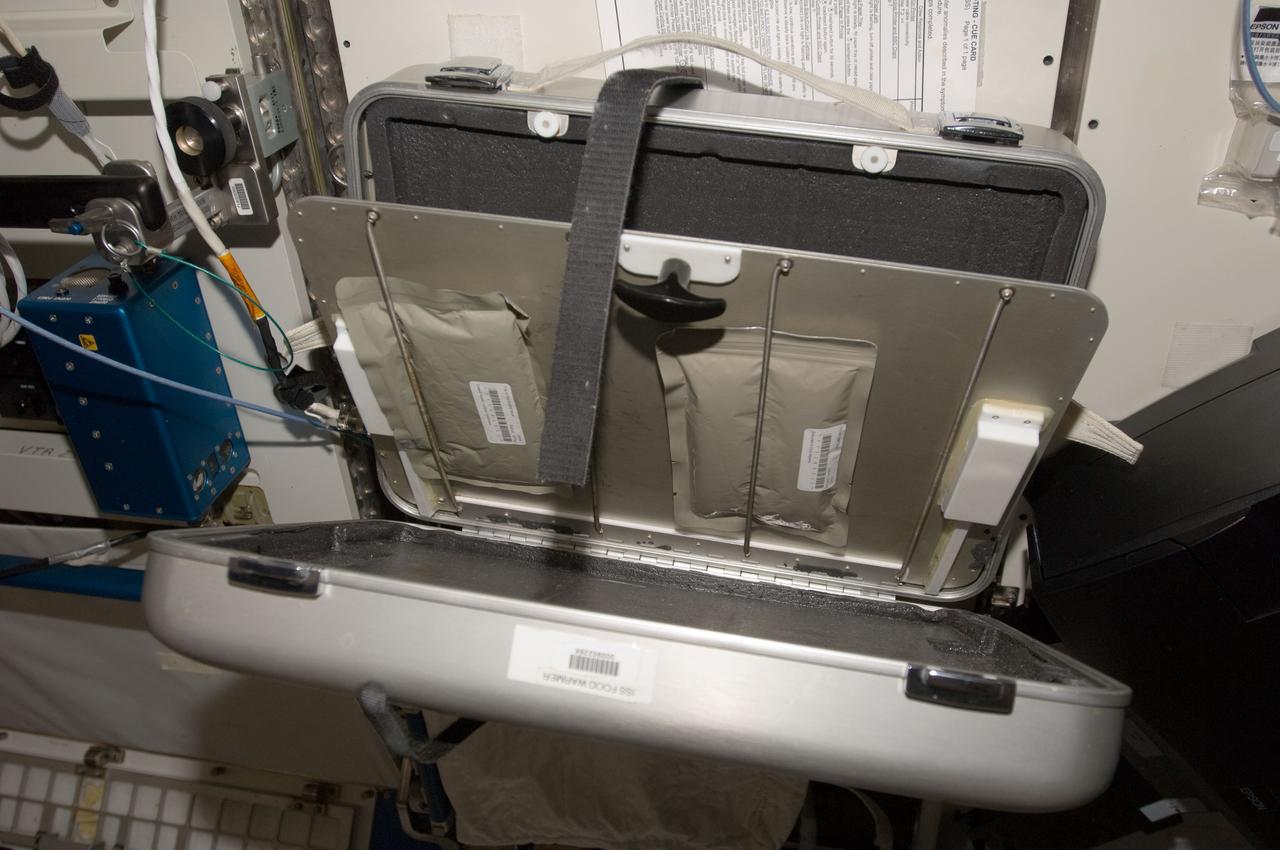 View of food packets tied down within suitcase.  Photo was taken during Expedition 34.