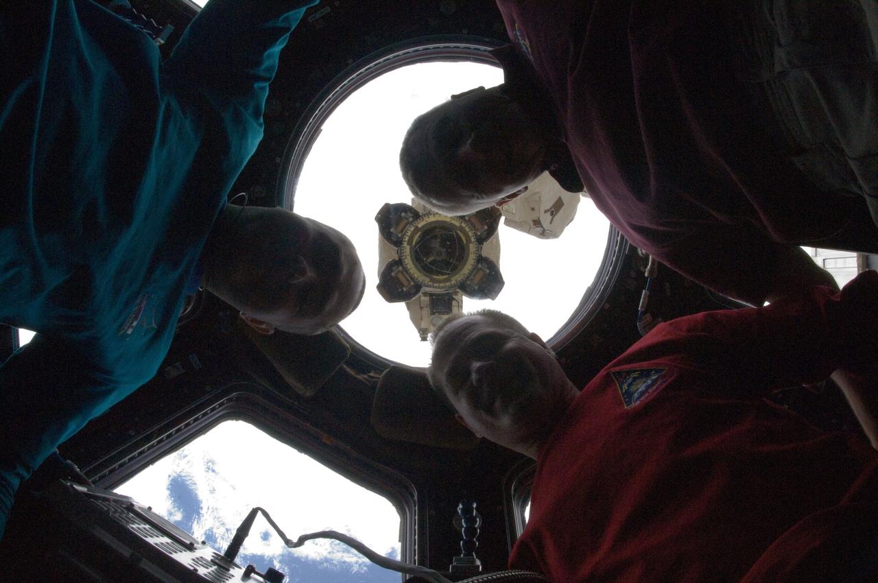 ISS034-E-010955 (27 Nov. 2012) --- NASA astronaut Kevin Ford (lower right), Expedition 34 commander; along with Russian cosmonauts Evgeny Tarelkin (left) and Oleg Novitskiy, both flight engineers, are partially silhouetted as they pose for a photo in the Cupola of the International Space Station. The Canadarm2 robotic arm's Latching End Effector (LEE) is visible through a window in the background.