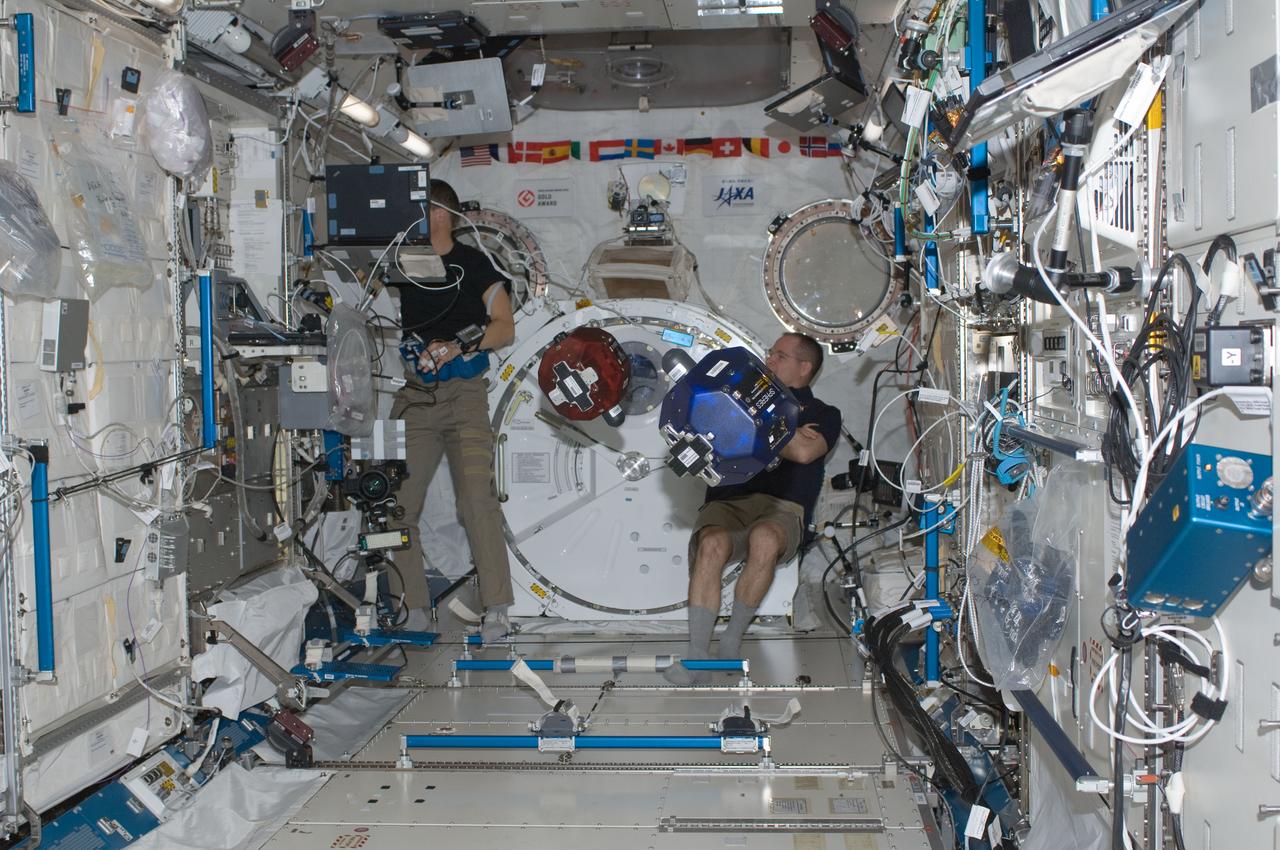 ISS034-E-014548 (4 Jan. 2013) --- With their feet anchored in floor restraints, NASA astronauts Kevin Ford (right), Expedition 34 commander; and Tom Marshburn, flight engineer, conduct a session of the Synchronized Position Hold, Engage, Reorient, Experimental Satellites (SPHERES) program in the Kibo laboratory of the International Space Station.