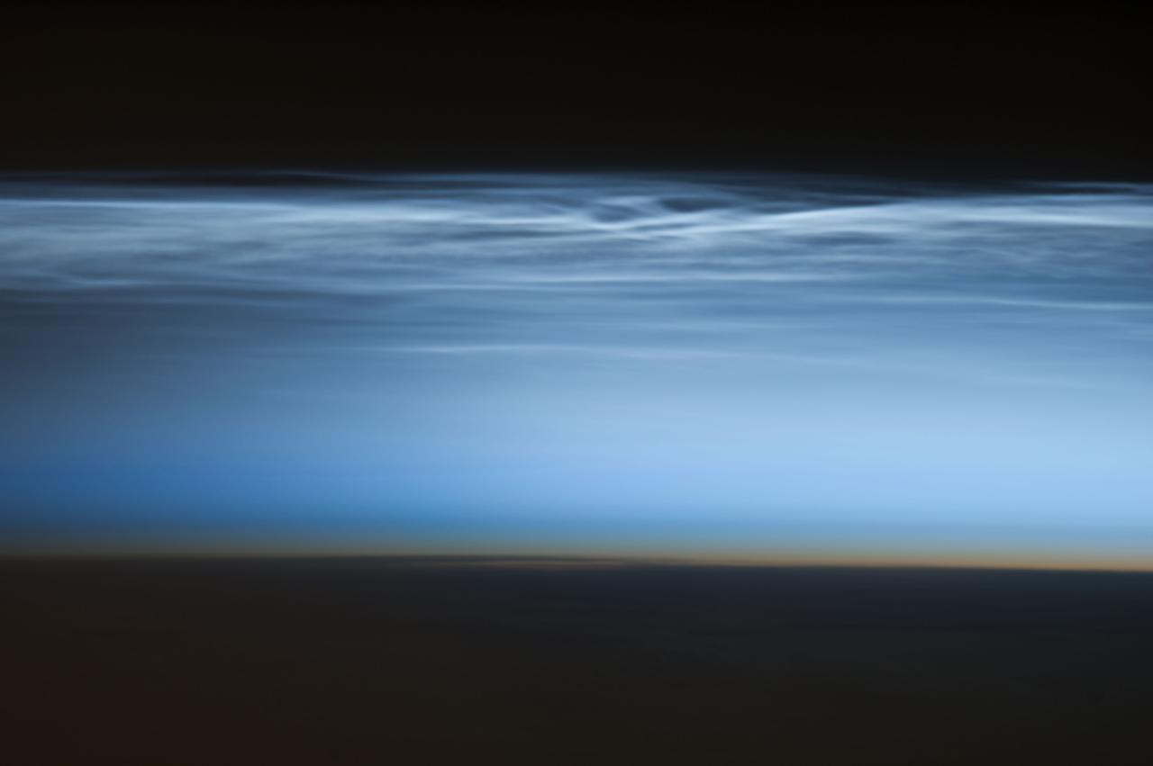 ISS034-E-024622 (5 Jan. 2013) --- Polar mesospheric clouds over the South Pacific Ocean are featured in this image photographed by an Expedition 34 crew member on the International Space Station. Polar mesospheric clouds—also known as noctilucent, or “night shining” clouds—are formed 76 to 85 kilometers above Earth’s surface near the mesosphere-thermosphere boundary of the atmosphere, a region known as the mesopause. At these altitudes, water vapor can freeze into clouds of ice crystals. When the sun is below the horizon such that the ground is in darkness, these high clouds may still be illuminated—lending them their ethereal, “night shining” qualities. Noctilucent clouds have been observed from all human vantage points in both the Northern and Southern Hemispheres – from the surface, in aircraft, and in orbit from the space station—and tend to be most visible during the late spring and early summer seasons. Polar mesospheric clouds also are of interest to scientists studying the atmosphere. While some scientists seek to understand their mechanisms of formation, others have identified them as potential indicators of atmospheric changes resulting from increases in greenhouse gas concentrations. This photograph was taken when the station was over the Pacific Ocean south of French Polynesia. While most polar mesospheric cloud images are taken from the orbital complex with relatively short focal length lens to maximize the field of view, this image was taken with a long lens (400 mm) allowing for additional detail of the cloud forms to be seen. Below the brightly-lit noctilucent clouds in the center of the image, the pale orange band indicates the stratosphere.