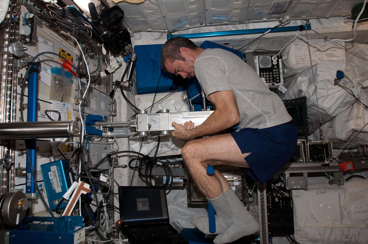 View of Canadian Space Agency (CSA) Chris Hadfield, Expedition 34 Flight Engineer (FE), using the Space Linear Acceleration Mass Measurement Device (SLAMMD) in the Columbus Module. Photo was taken during Expedition 34.