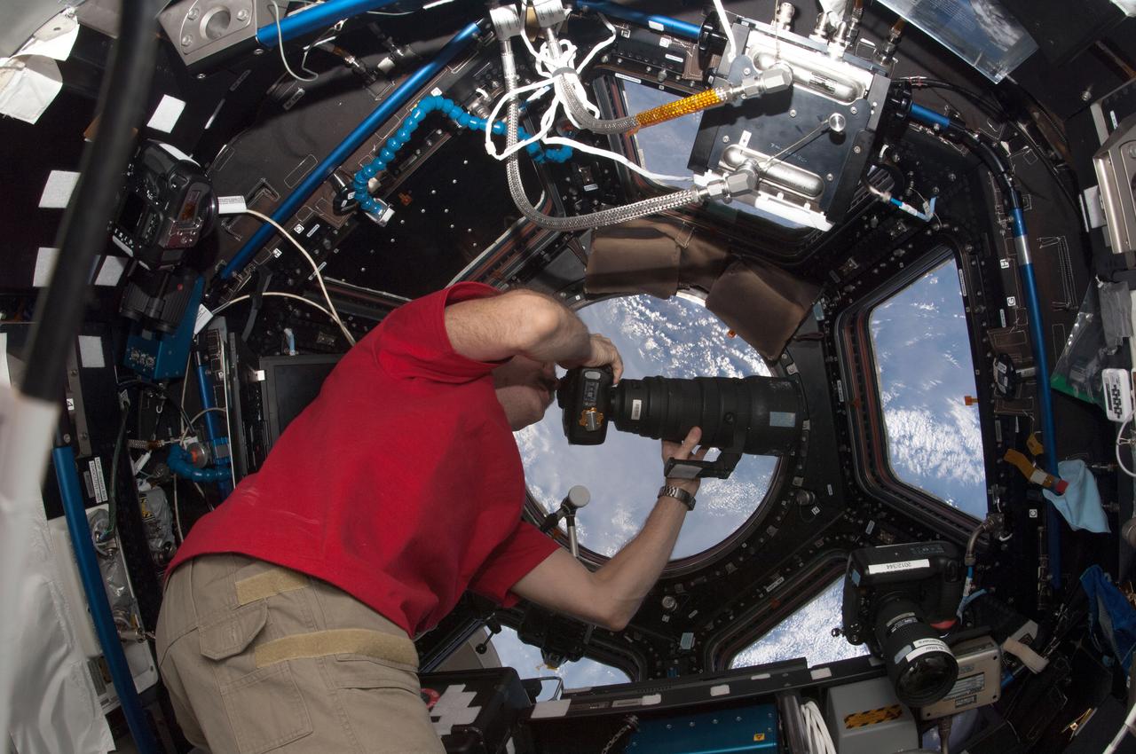 ISS034-E-027234 (7 Jan. 2013) --- Canadian Space Agency astronaut Chris Hadfield, Expedition 34 flight engineer, uses a camera to photograph the topography of a point on Earth from a window in the Cupola of the International Space Station.