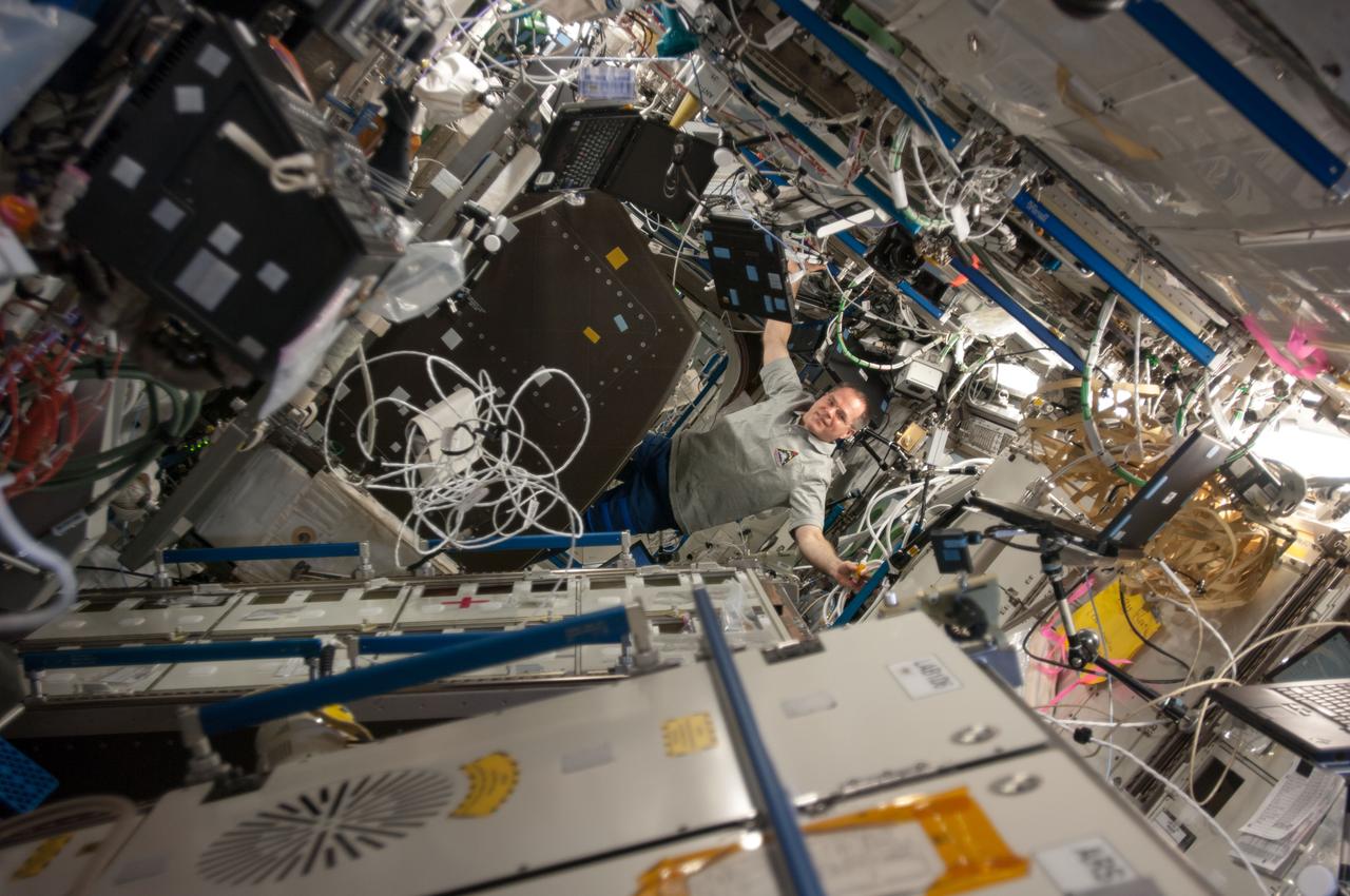 ISS034-E-030218 (16 Jan. 2013) --- NASA astronaut Kevin Ford, Expedition 34 commander, installs a Ultra-Sonic Background Noise Tests (UBNT) sensor kit behind a rack in the Destiny of the International Space Station.