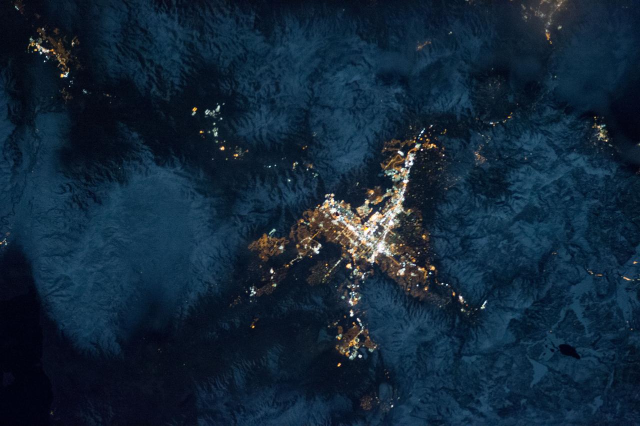 ISS034-E-035548 (28 Jan. 2013) --- A nighttime view of the Reno, Nevada metropolitan area is featured in this image photographed by an Expedition 34 crew member on the International Space Station. Known as ?the biggest little city in the world?, the city of Reno is located in Truckee Meadows along the eastern foothills of the Sierra Nevada near the California border. It forms part of the Reno-Sparks metropolitan area?the largest such area in northern Nevada, and the second largest in the state after Las Vegas. Lake Tahoe, a major destination for skiing and other outdoor recreational activities, is located less than 50 kilometers to the southwest of the Reno-Sparks metro area. The relatively isolated nature of the metropolitan area within the surrounding terrain is highlighted in this nighttime image. The major industrial and commercial areas of both Reno and Sparks are brightly lit at center. The major street grid is visible as orange linear features adjacent to the industrial/commercial areas. Residential areas appear dark in contrast. The Reno-Tahoe International Airport (center) is visible as a dark, dagger-shaped region in the southeast quarter of the metropolitan area. At the time this photograph was taken, the moon was in a waning gibbous phase (98 percent of a full moon). Moonlight provided enough illumination of the ground surface such that the topography, accentuated by snow cover, surrounding the Reno-Sparks area is clearly visible (upper right, lower right) following color enhancement.